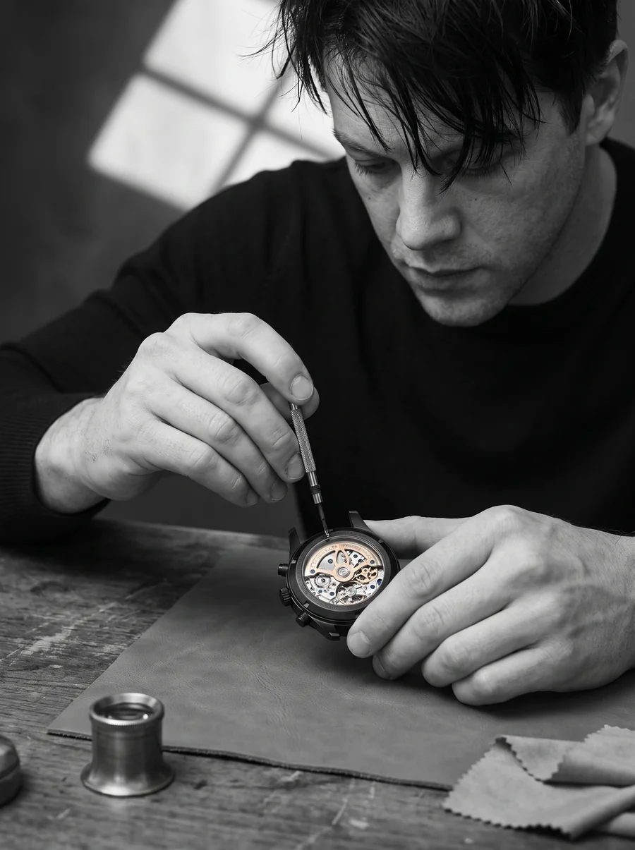 Devin Mercier working on a Mercier Prototype Manx at the bench, tiny screwdriver touching the movement